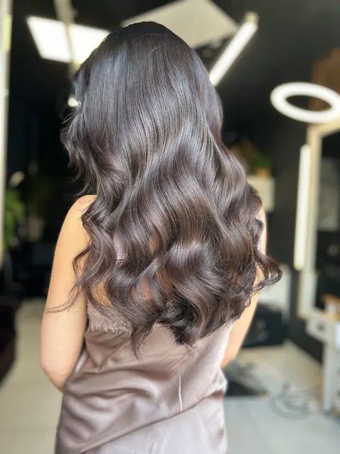 Hosszú, csokoládébarna haj fényes, kidolgozott hullámokkal, hátulról fotózva a marosvásárhelyi BLOOM Hair Salonban