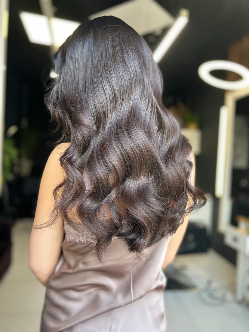 Hosszú, csokoládébarna haj fényes, kidolgozott hullámokkal, hátulról fotózva a marosvásárhelyi BLOOM Hair Salonban