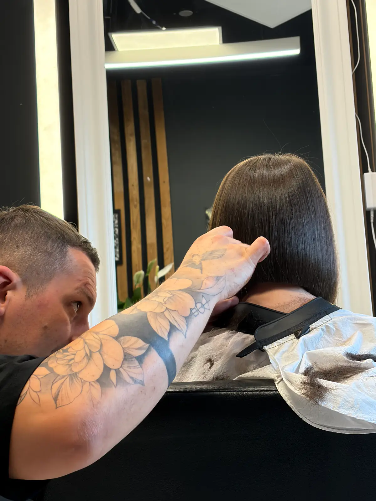 Attila checking a bob's symmetry in the salon mirror before the final cuts